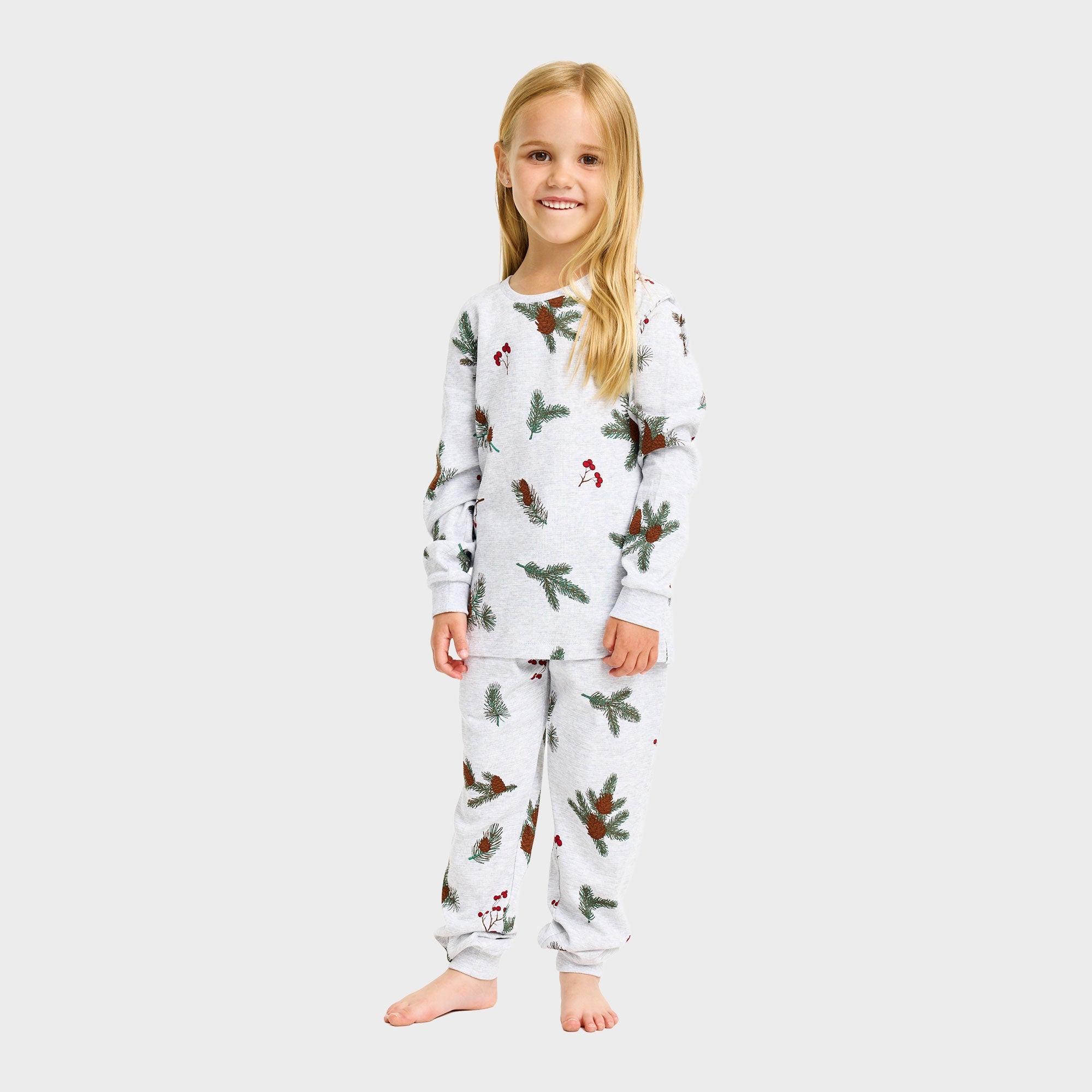 Weihnachtspyjama Kinder aus weißem Bio-Baumwoll-Jersey mit Tannenzweigen und Weihnachtsornamenten.