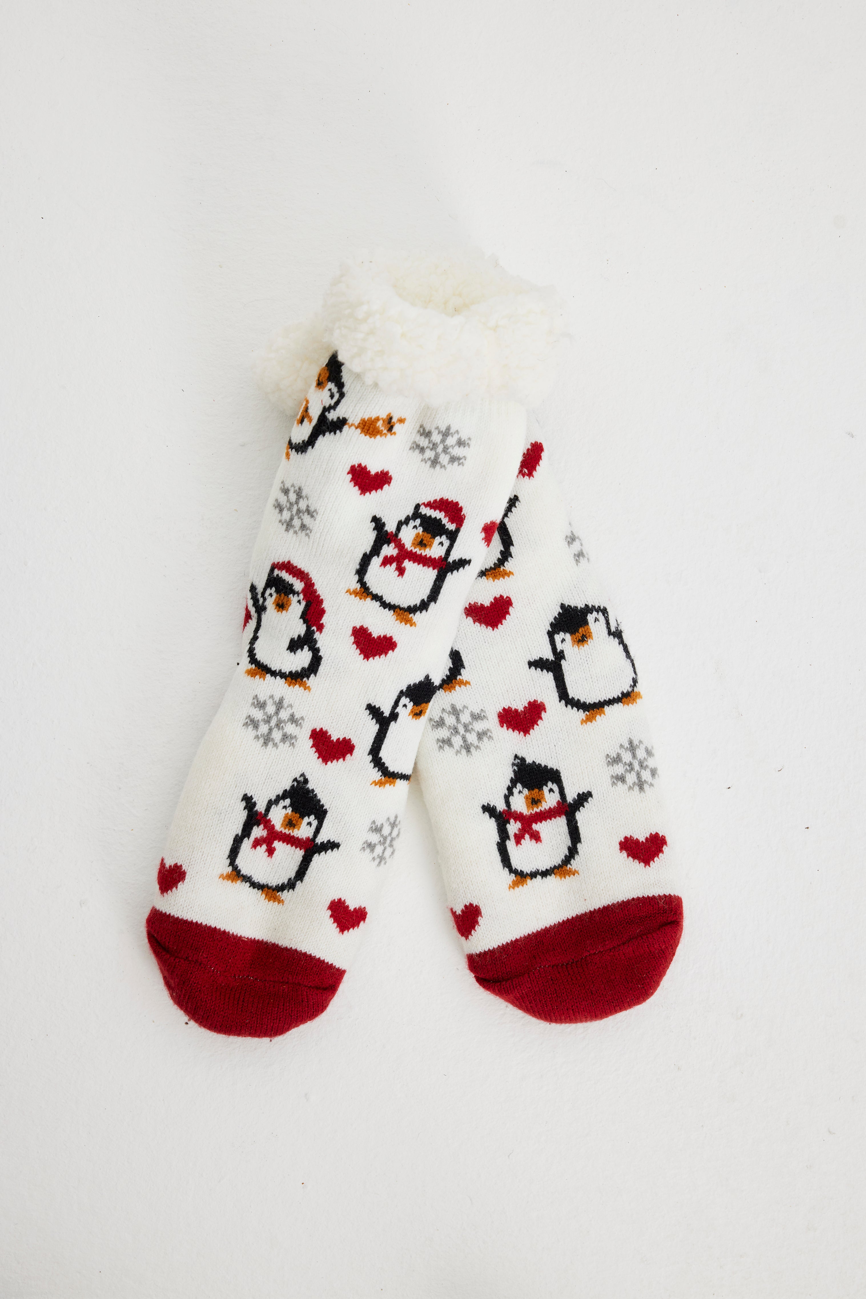 Ein Paar rote und weiße Weihnachtssocken mit Pinguinen darauf.