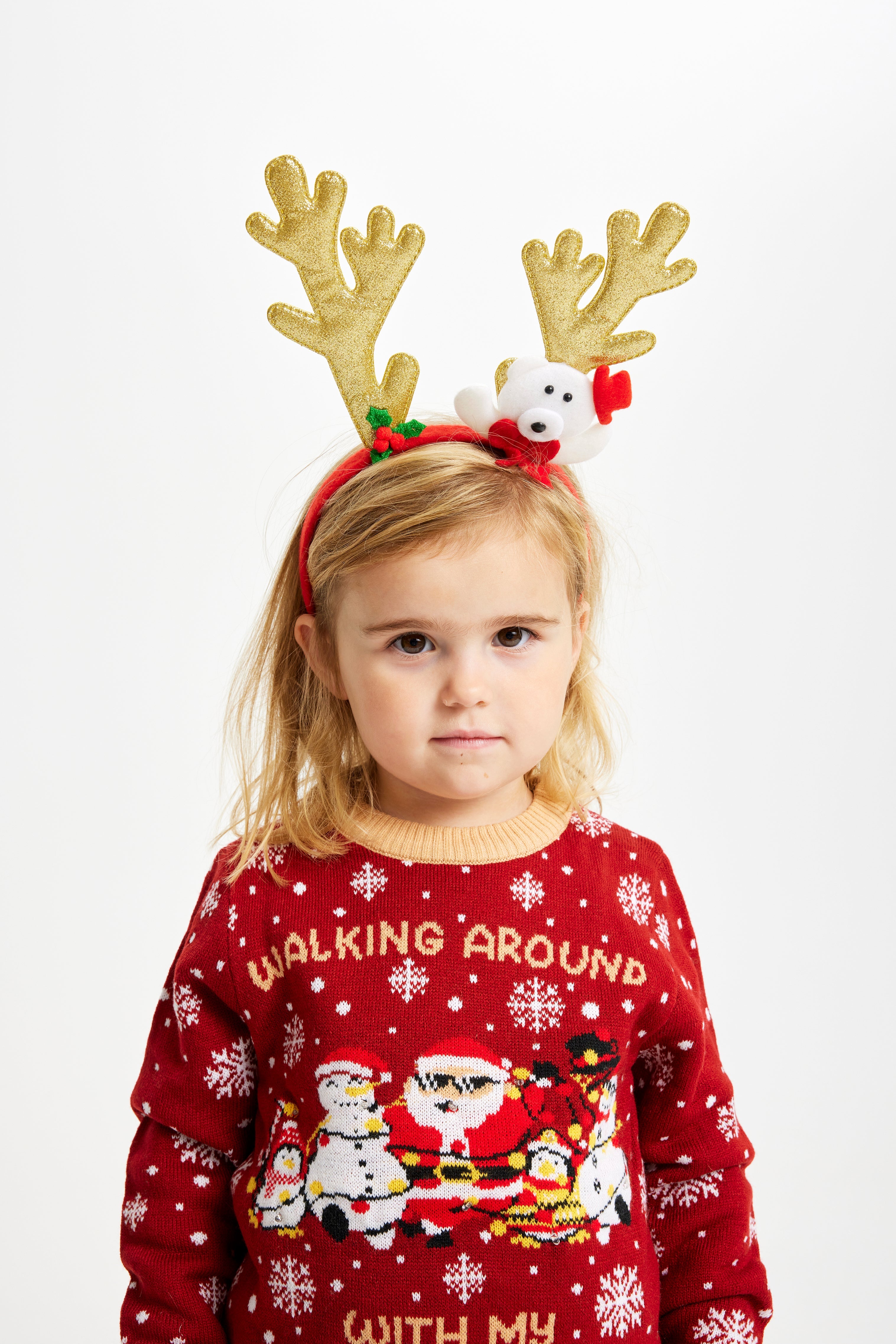Ein Kind mit Rentiergeweih und einem roten Weihnachtspulli mit dem Spruch 