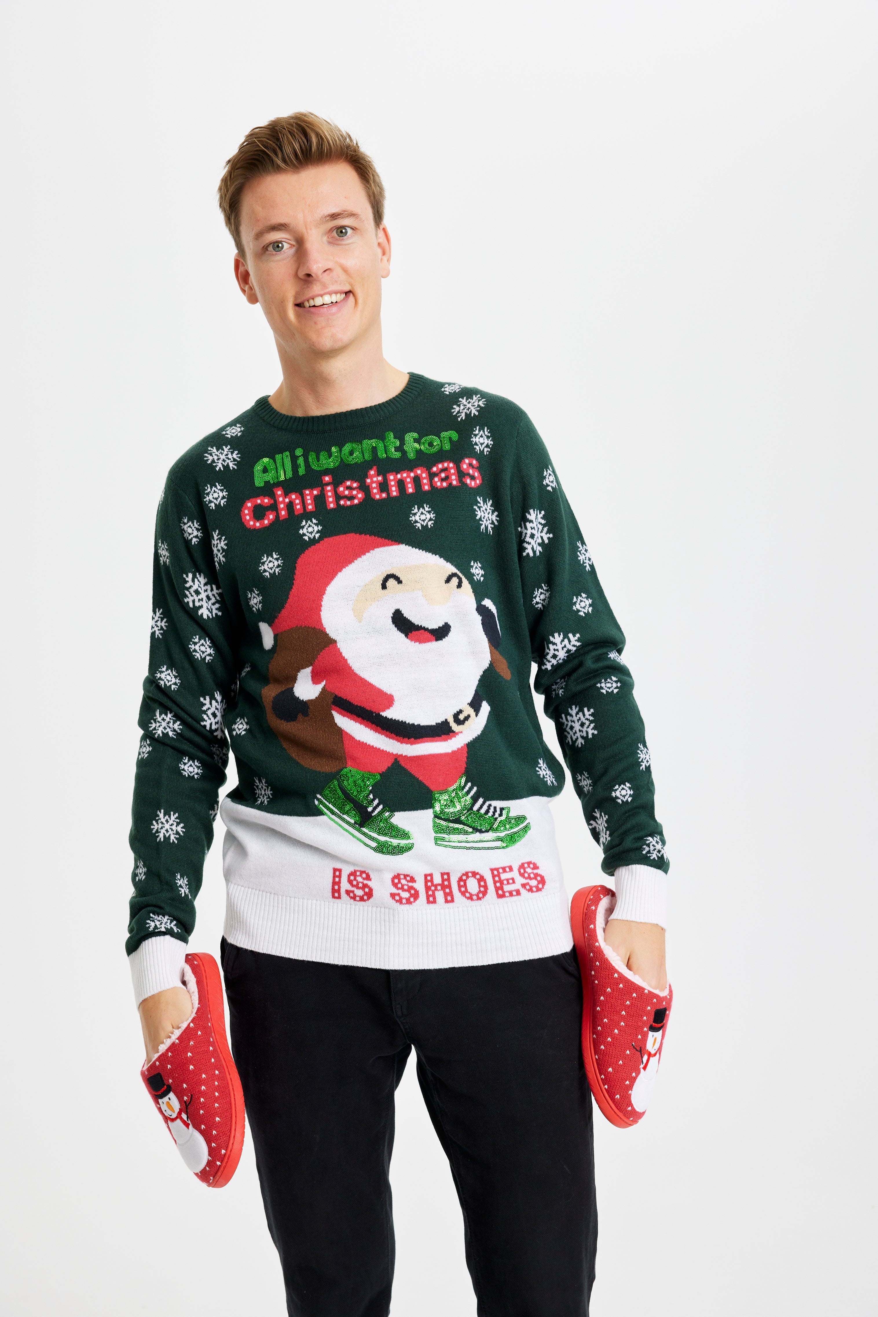 Eine posierende Frau, die einen grün-weißen Weihnachtspulli mit dem Spruch 