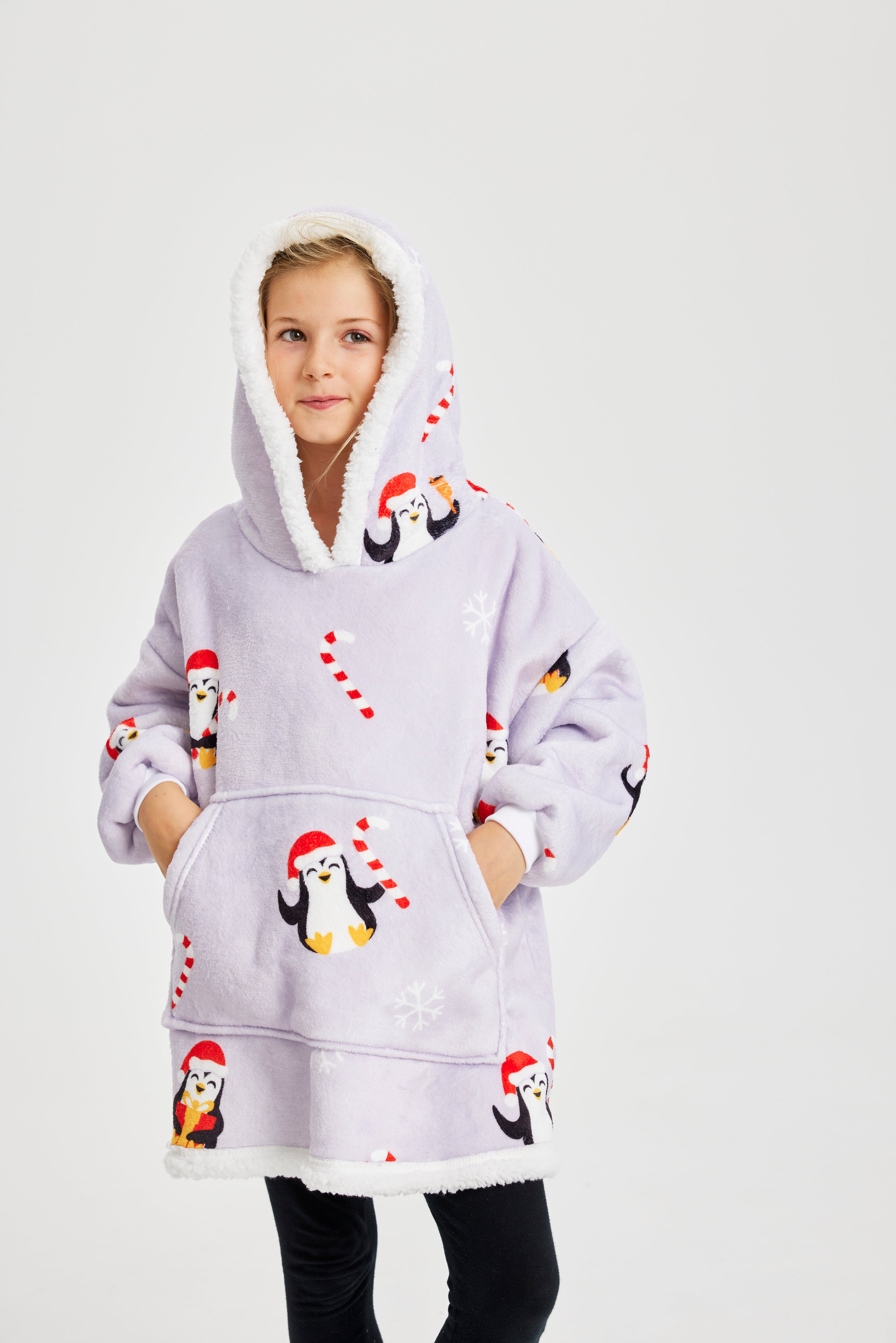 Ein Kind mit einem hellvioletten Weihnachtskapuzenpullover mit Pinguinen darauf.