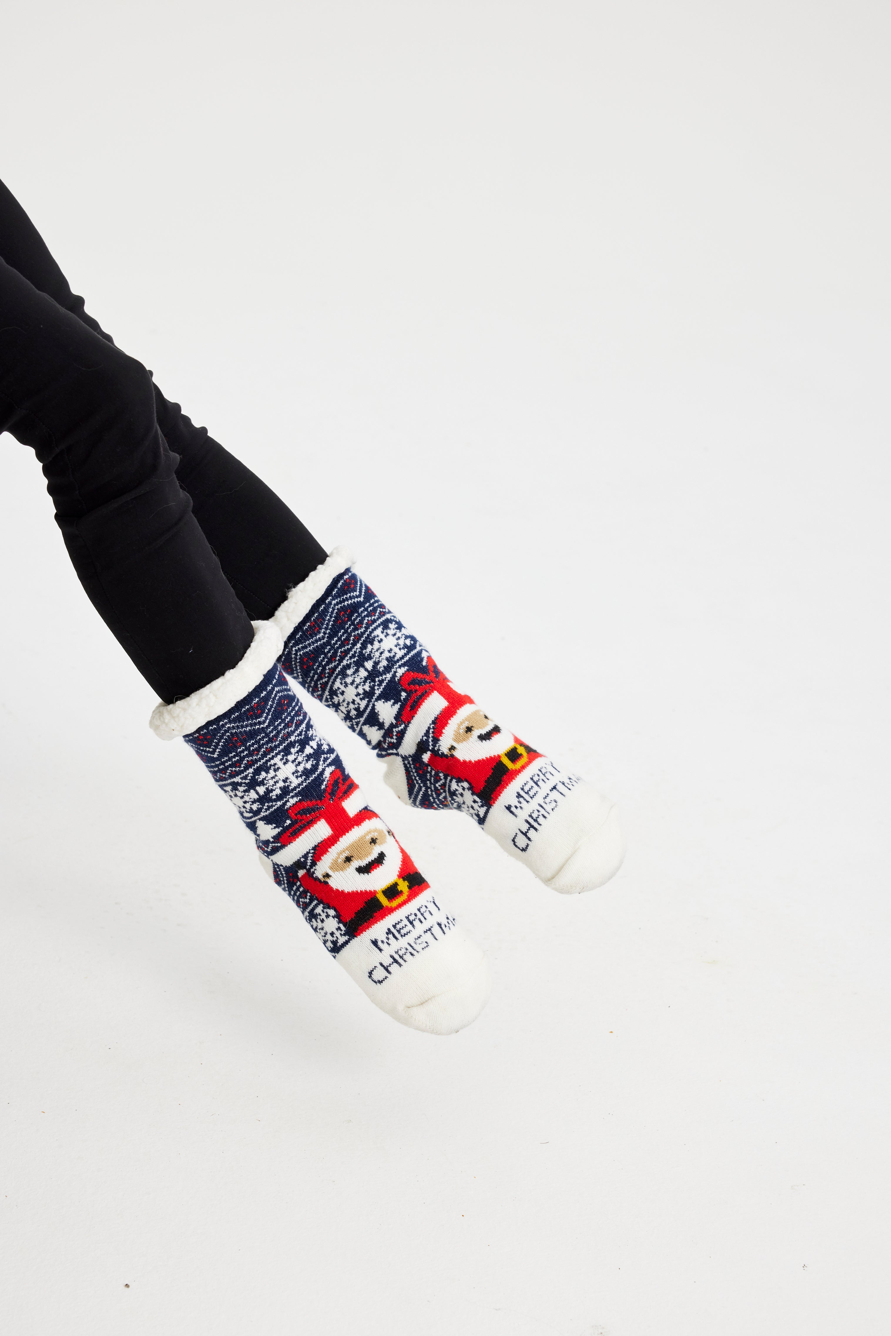 Ein Paar Beine, die ein Paar Weihnachtssocken mit dem Weihnachtsmann darauf tragen.