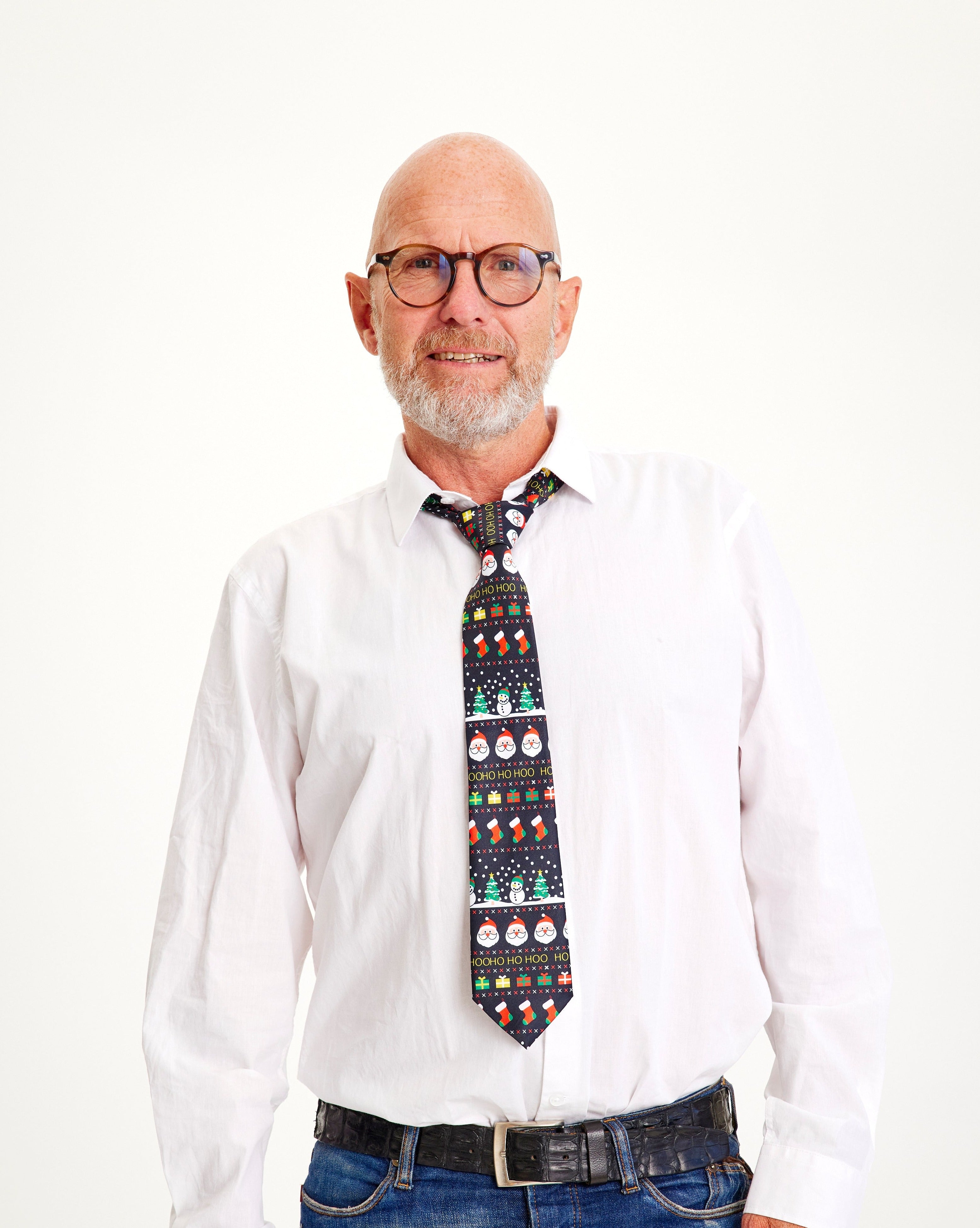 Ein lächelnder Mann trägt eine dunkle Weihnachtskrawatte mit einem Weihnachtsmuster.